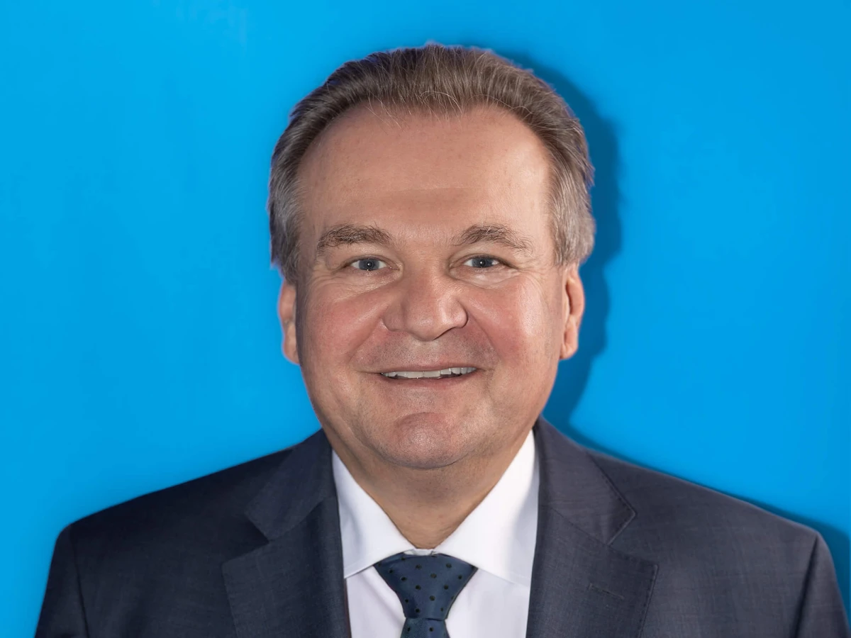 A portrait of a smiling CEO in front of a light blue background. This professional portrait photo is ideal for LinkedIn profiles and other business uses.