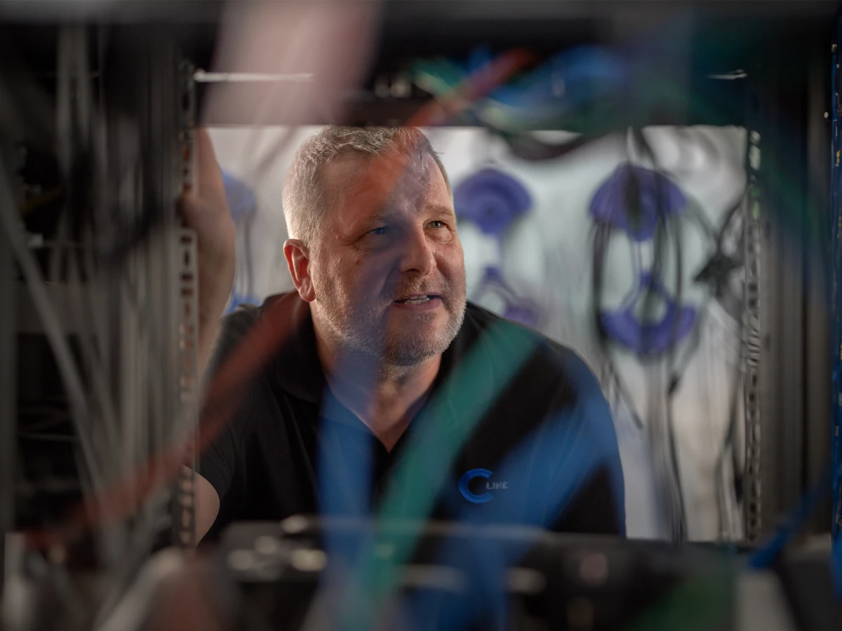 A technician works diligently in a server room, surrounded by cables and technical equipment. This image showcases the company’s technical expertise and commitment, perfect for introducing the team and key contacts on the website.